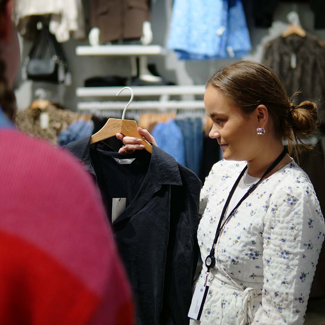Only medarbejder som er ved at fremvise en jakke for en kunde i Glostrup